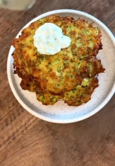 Delicious crispy zucchini pancake served on a plate garnished with herbs