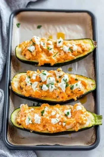High protein buffalo chicken stuffed zucchini boats served on a white plate