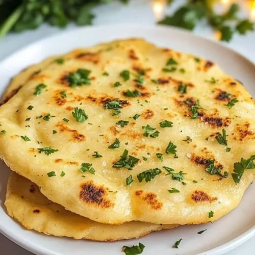Delicious Keto Naan Bread served on a wooden table with fresh herbs.