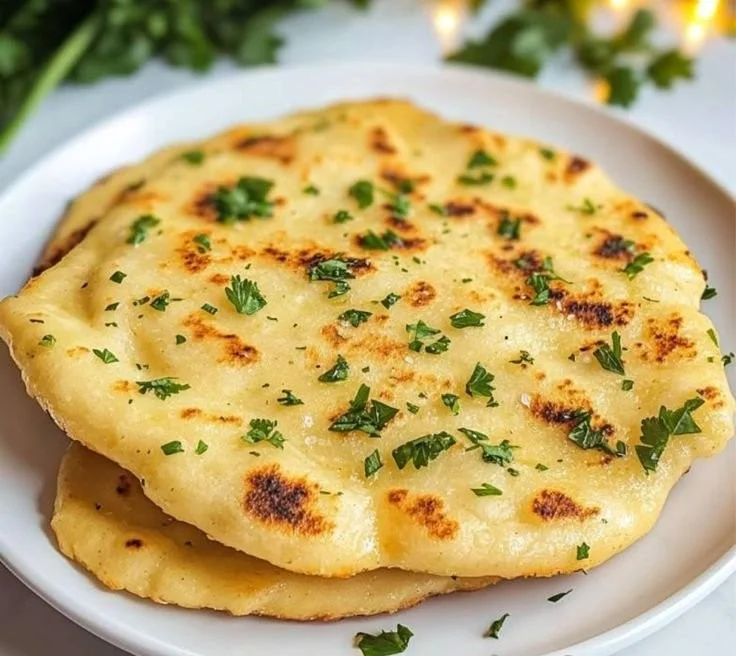 Delicious Keto Naan Bread served on a wooden table with fresh herbs.
