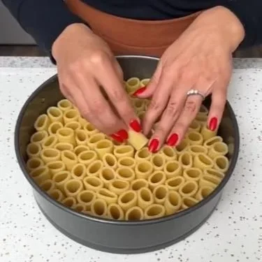 A plate of rigatoni pasta served with marinara sauce and basil.