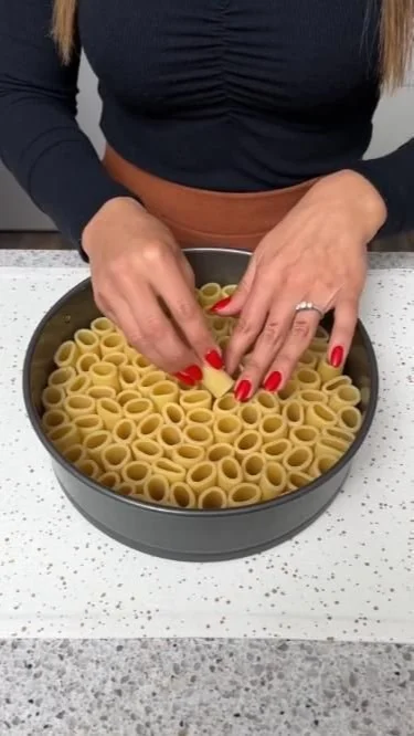 A plate of rigatoni pasta served with marinara sauce and basil.